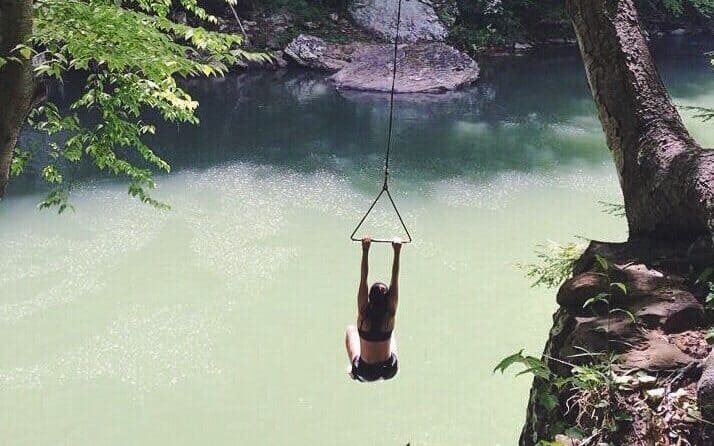 Woman rope swinging into a river